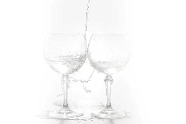 Acqua versata dalla bottiglia nel bicchiere, isolata su bianco — Foto Stock