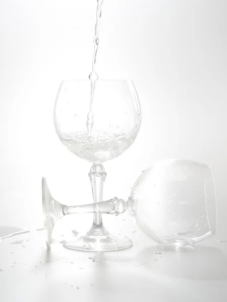 Acqua versata dalla bottiglia nel bicchiere, isolata su bianco — Foto Stock