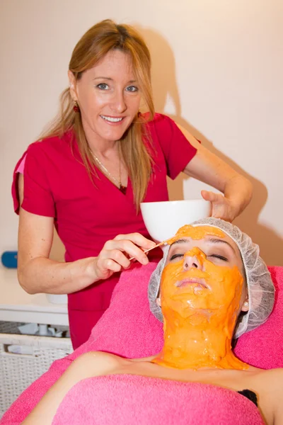 Entspannende Frau mit Tongesichtsmaske von Kosmetikerin. — Stockfoto