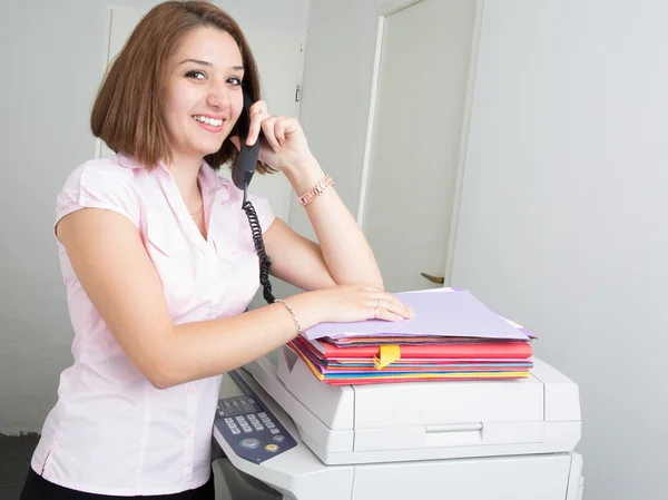 Mulher bonita usando uma máquina de cópia e telefone — Fotografia de Stock