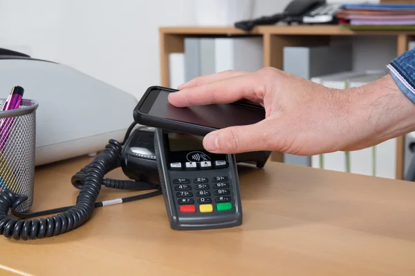 Man paying for good with NFC technology on mobile phone — Stock Photo, Image