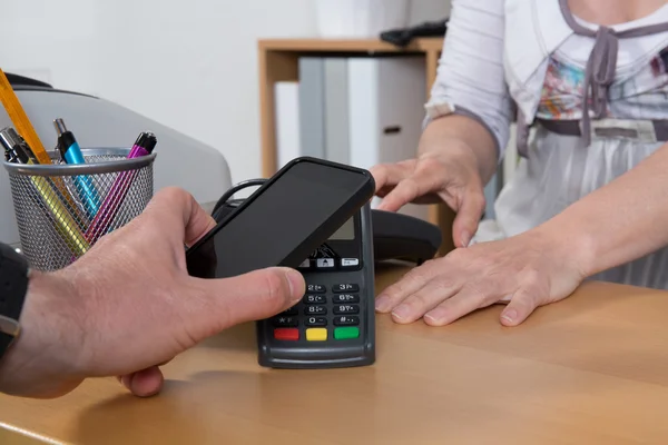 Masculino pagando para o bem com a tecnologia NFC no telefone móvel — Fotografia de Stock