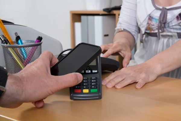 Hombre pagando por el bien con la tecnología NFC en el teléfono móvil —  Fotos de Stock