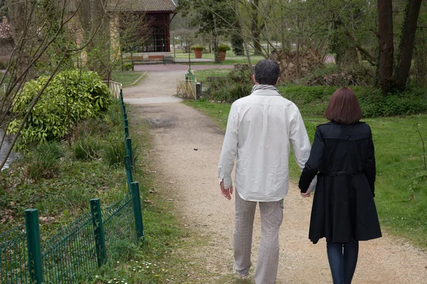 Ζευγάρι περπατά στον κήπο την άνοιξη, κρατώντας στα χέρια τους. — Φωτογραφία Αρχείου