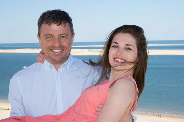 Ler par på semester kramas över stranden bakgrund — Stockfoto