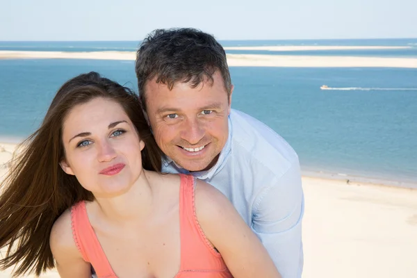 Smiling couple on vacation hugging over beach background — Stock Photo, Image