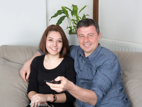 Smiling couple watching tv on the couch at home — Stock Photo, Image