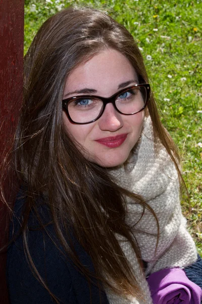 Sorrindo adolescente menina vestindo óculos, sentado no verão parque verde — Fotografia de Stock