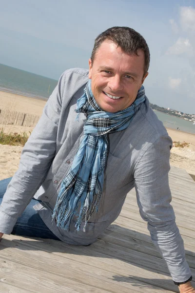 Handsome middle aged man sitting at the beach — Stock Photo, Image