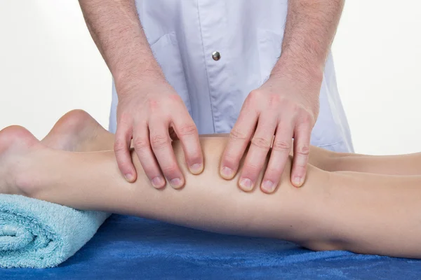 Mani massaggiare il muscolo del polpaccio umano. terapeuta applicando pressione sulla gamba femminile . — Foto Stock