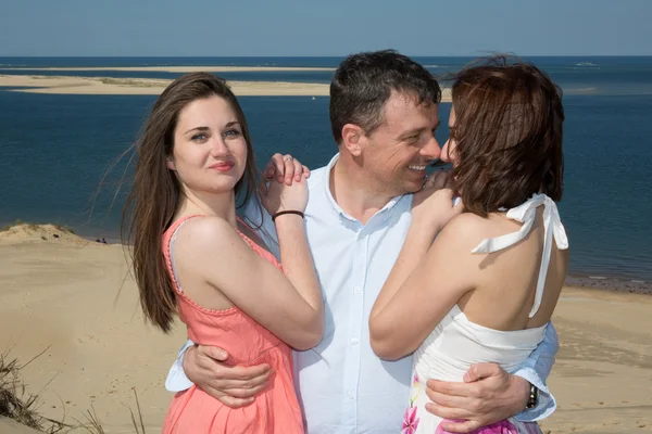 男人亲吻一个女孩和拥抱另一个，在海边 — 图库照片
