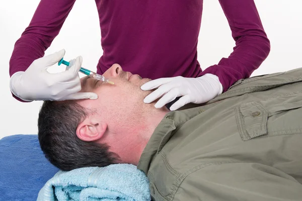 Doctor in glove giving injection on face of man in clinic — Stock Photo, Image