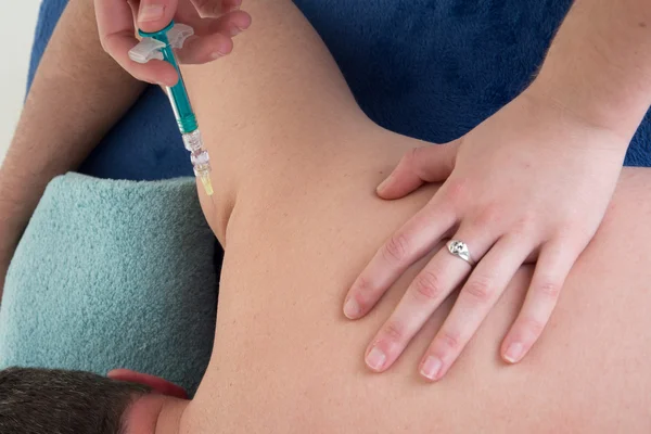 Unga läkare kvinnor ge en injektion i axeln av en man — Stockfoto