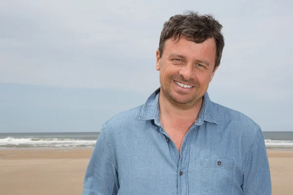 Portrait d'un homme d'âge moyen debout à la plage souriant — Photo