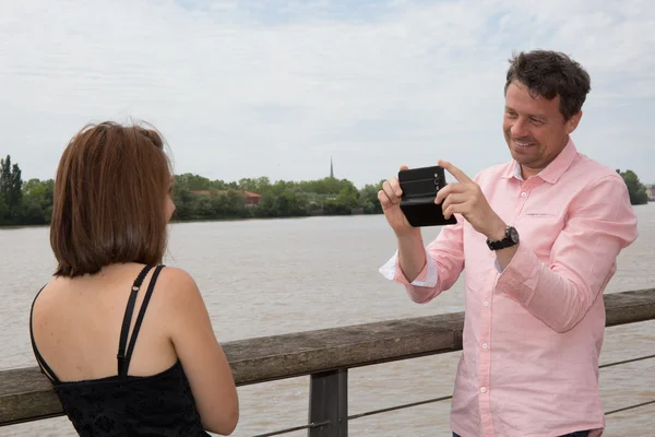Glimlachende man fotograferen met zijn mobiele van een vrouw — Stockfoto