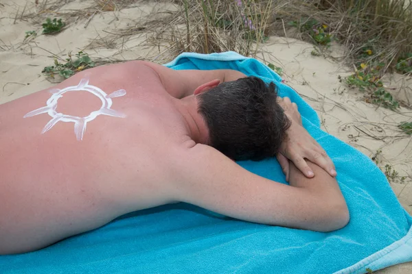 Stosując suncream na plaży z symbolem słońca — Zdjęcie stockowe