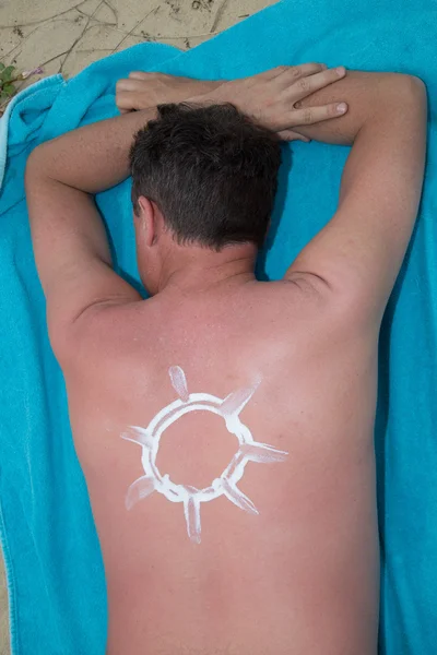 Applying suncream on the beach with the symbol of sun — Stock Photo, Image