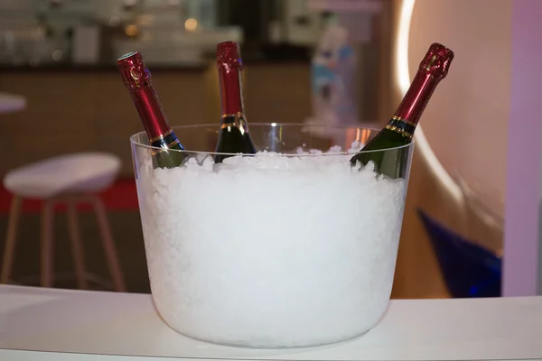 Trzy butelki szampana w wiaderku z lodem na białym — Zdjęcie stockowe