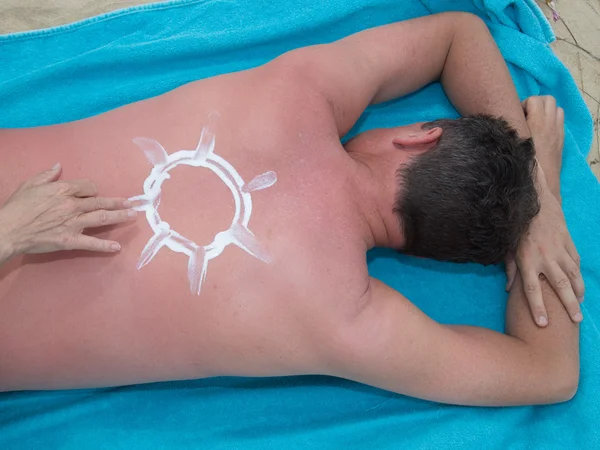 Handen toepassing van zonnebrandcrème op strand met het symbool van de zon — Stockfoto