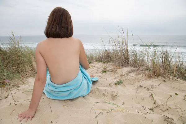 Mujer bonita desnuda sentada por la espalda en la playa — Foto de Stock