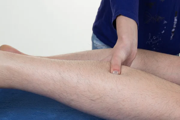 Masowania mięśni łydki ludzkich rąk. Kobiece terapeuta wywierania nacisku na mężczyzna noga. — Zdjęcie stockowe