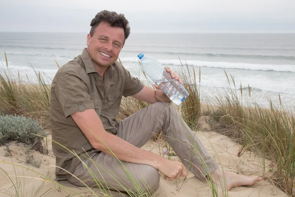 Sorridente uomo caucasico in posa in spiaggia - acqua potabile — Foto Stock