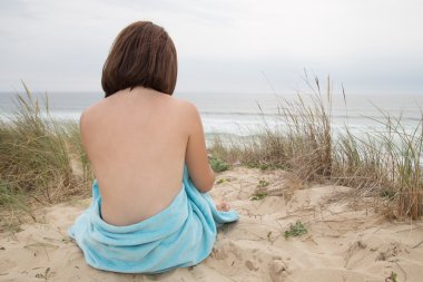 Beautiful woman nude sitting from the back on beach clipart