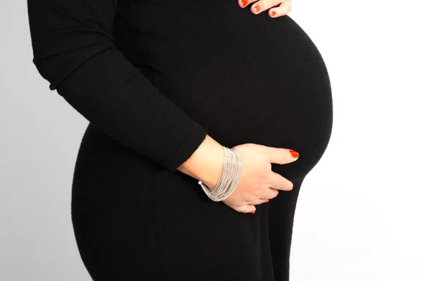 Sexy zwangere vrouw in een zwarte jurk houden haar buik — Stockfoto