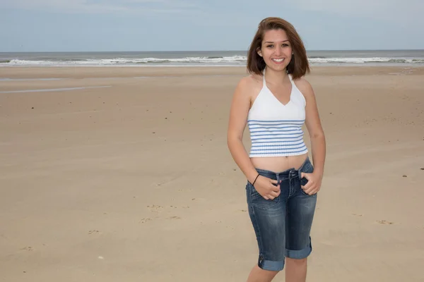Улыбающаяся случайная женщина, стоящая на пляже — стоковое фото