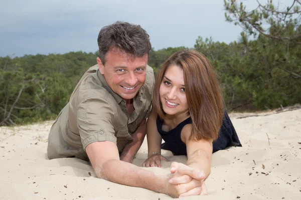 Glückliches schönes Paar, das Spaß am Meer, auf den Sandkörnern hat — Stockfoto