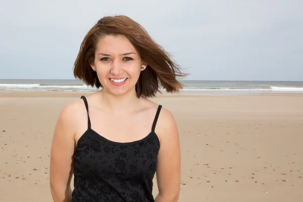 Sonriente chica morena en vestido negro posando en la playa —  Fotos de Stock