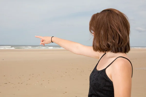 Bruneta žena na pláži, ukazující prst — Stock fotografie