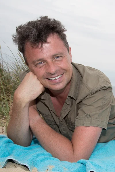 Homme sur la plage couché dans le sable regardant caméra — Photo