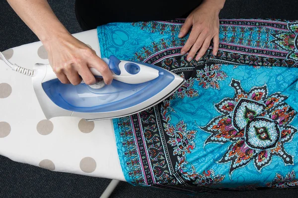 Flat lay of woman using an iron for blue dress — Stock Photo, Image