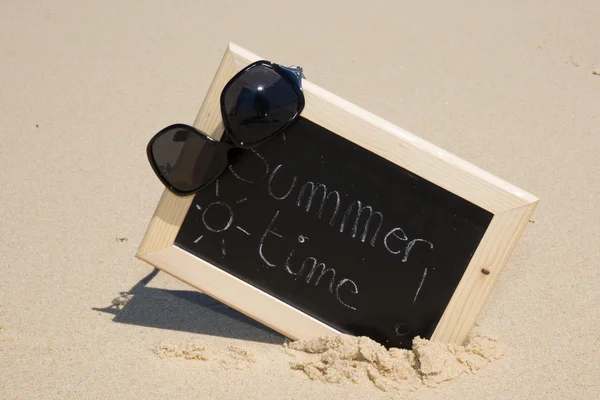 Chalkboard with the text summer time on sand of beach — Stock Photo, Image