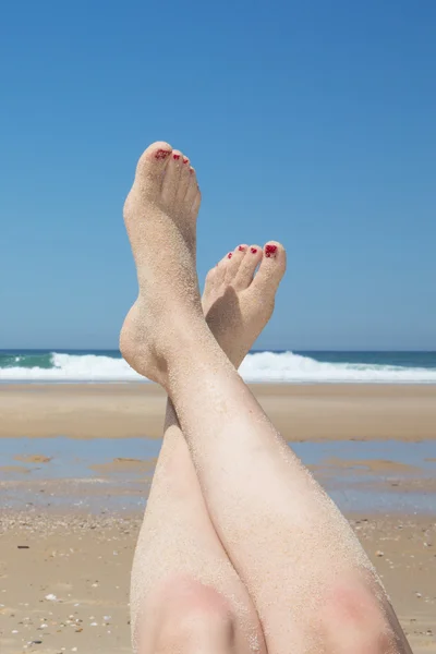Vrouw zonnebaden op tropische strand. Benen. Stockfoto