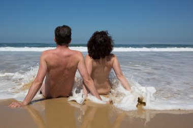 Couple in the water at the beach, backside to camera clipart