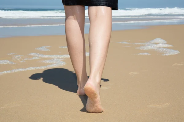 Donna che cammina sulla spiaggia di sabbia lasciando impronte sulla sabbia. — Foto Stock