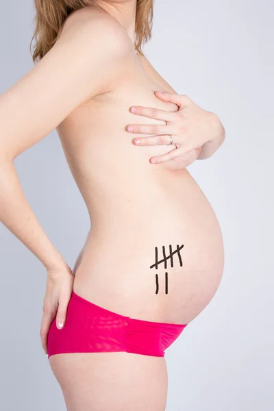 怀孕的女人抱着她双手放在她的身体上 — 图库照片