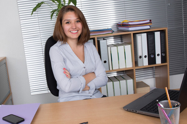 Portrait of business woman sitting with crossed arms in office