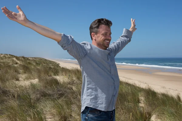 Uomo sulla spiaggia tenere le mani in alto, vista posteriore ragazzo indossa camicia — Foto Stock