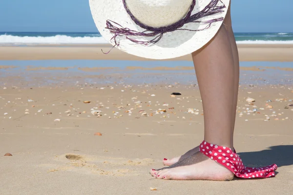 Mujer en la playa sosteniendo sombrero teniendo bikini a pie —  Fotos de Stock