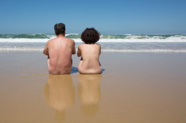 Couple in the water at the beach, backside to camera clipart