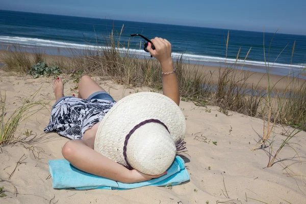 Chica feliz con un sombrero tirado en la playa — Foto de Stock