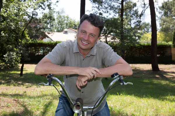 Glimlachend wielrenner leunend op zijn fiets onderweg bos. — Stockfoto