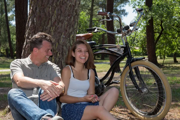 Pareja en vacaciones relajándose cerca de un árbol después de andar en bicicleta — Foto de Stock