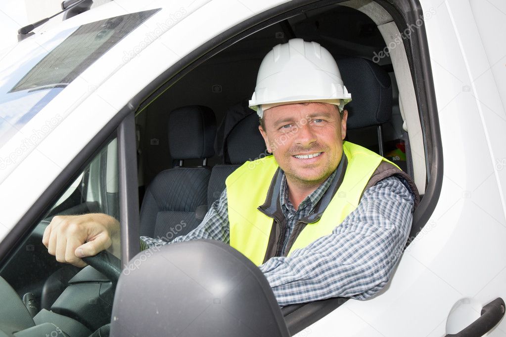 Construction worker driving a car and talking, wearing white helmet