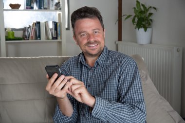 Kısa mesaj göndermek için cep telefonu kullanan adam