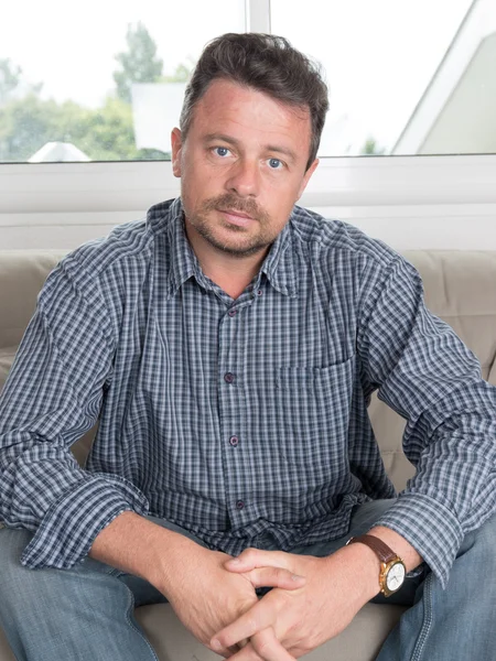 Portrait of worried senior man sitting on sofa in living room — Stock Photo, Image