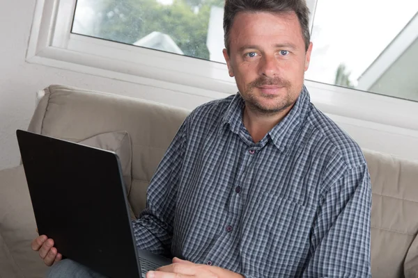 Uomo guardando e lavorando sul computer portatile a casa — Foto Stock